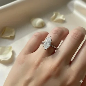 A stunning marquise solitaire diamond engagement ring on a woman's hand, showcasing the elegant, elongated shape of the diamond and a simple band setting.