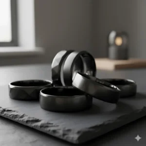 Collection of sleek, black wide wedding bands for men, showcasing different materials like ceramic or black tungsten.