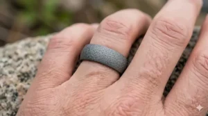 A man wearing a wide tungsten band with a coarse sandblast texture.
