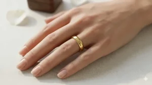 A person wearing a simple plain gold band on their ring finger to demonstrate scale and fit.