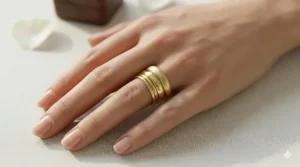 Multiple simple plain gold bands stacked together on a finger for a minimalist jewelry look.
