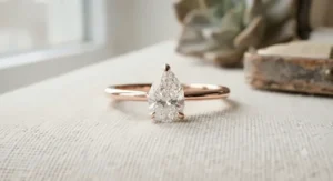 A modern minimalist rose gold pear shaped ring with a thin, sleek polished band.