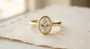 Modern yellow gold oval engagement ring with a sleek bezel setting.