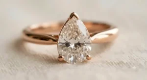 A macro close-up view of a rose gold pear shaped ring showcasing the gemstone's brilliant facets.