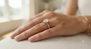 A stylish rose gold pear shaped ring worn elegantly on a model's hand.