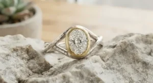 Artisanal two-tone oval-cut engagement ring highlighting a bezel setting and handcrafted mixed metals.