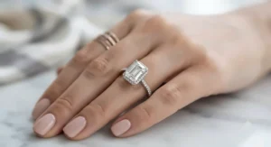 Hand modeling a luxurious white gold emerald cut diamond ring on a manicured finger.