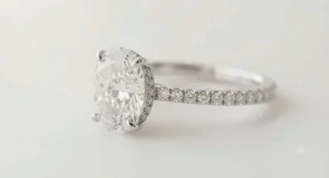 Pave band hidden halo oval diamond engagement ring sparkling brilliantly under studio lighting.