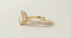 Yellow gold cushion cut ring with a diamond pave band viewed from a side angle