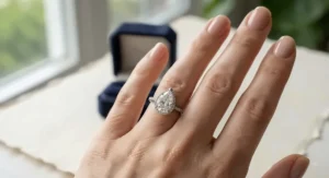 A close-up view of a pear-shaped engagement ring worn on a finger, highlighting the elongated silhouette that flatters the hand.