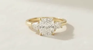Elegant three stone yellow gold cushion cut ring with side trapezoid diamonds