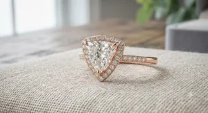 Luxurious trillion cut engagement ring framed by a delicate diamond halo setting on a rose gold band.
