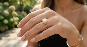 Hand model wearing a luxury yellow gold cushion cut ring outdoors in natural sunlight