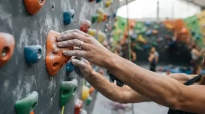 Close-up of women's wedding bands for active lifestyles on a climber's hand scaling an indoor rock wall.