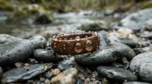 Water droplets beading on the surface of protected wood inlay wedding bands on river stones.